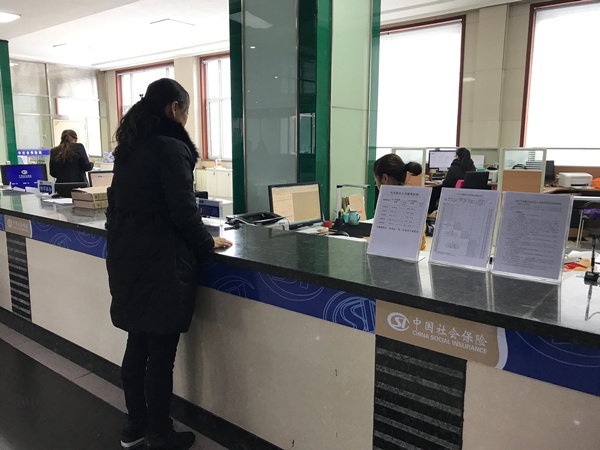 社区工作人员在社保局为老人办理资料